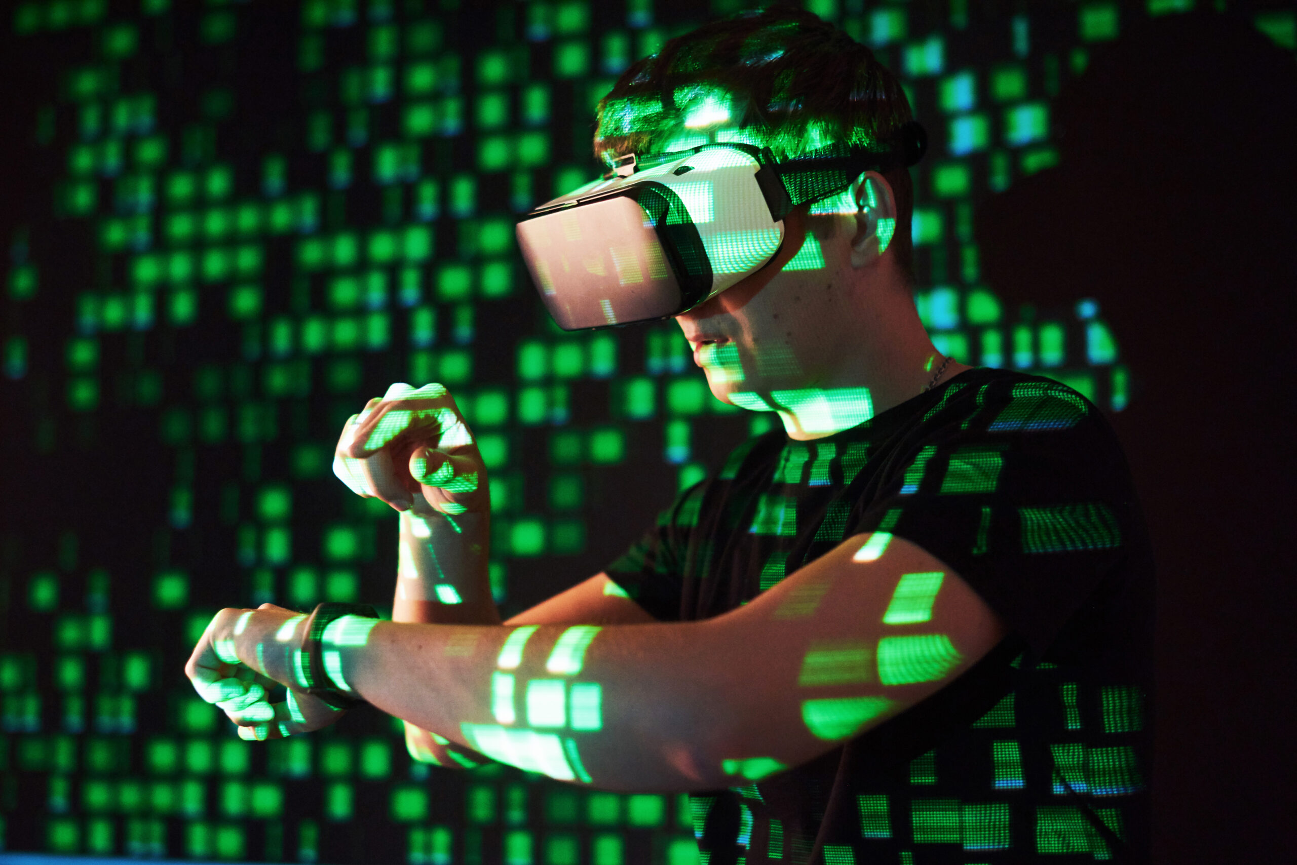 Double exposure of a caucasian man and Virtual reality VR headset is presumably a gamer or a hacker cracking the code into a secure network or server, with lines of code in green
